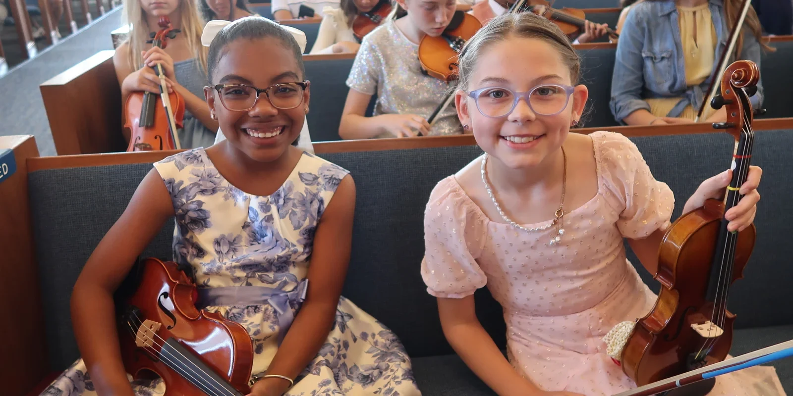 Students holding violins before a recital