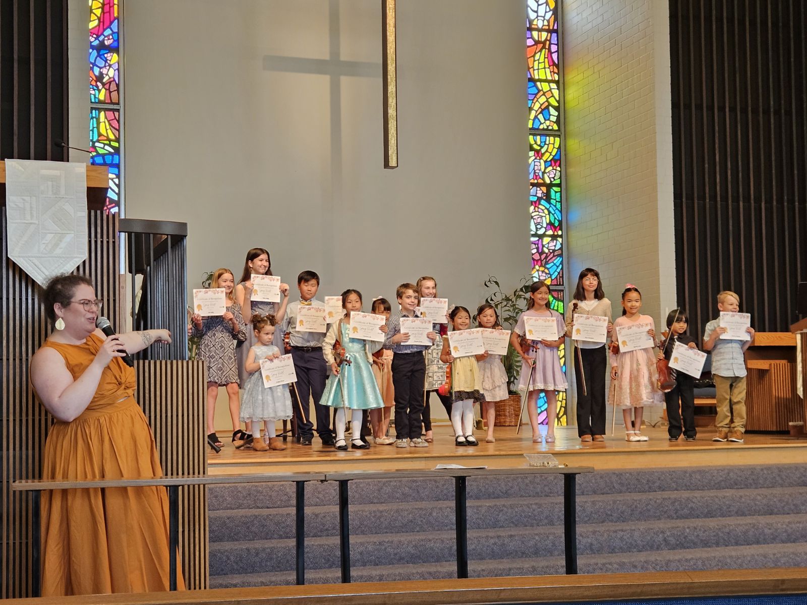 Emily Moore and students holding certificates after a recital